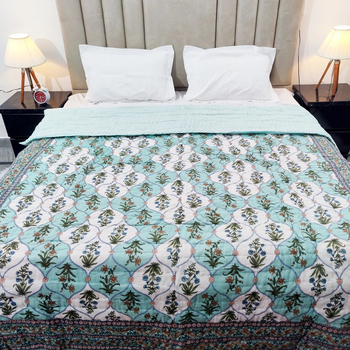 The Jaipuri cotton quilt for double bed block print in soothing green floral design spread on a bed